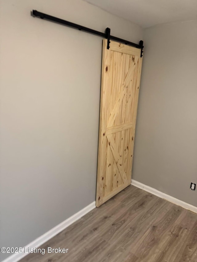 unfurnished room featuring wood-type flooring and a barn door