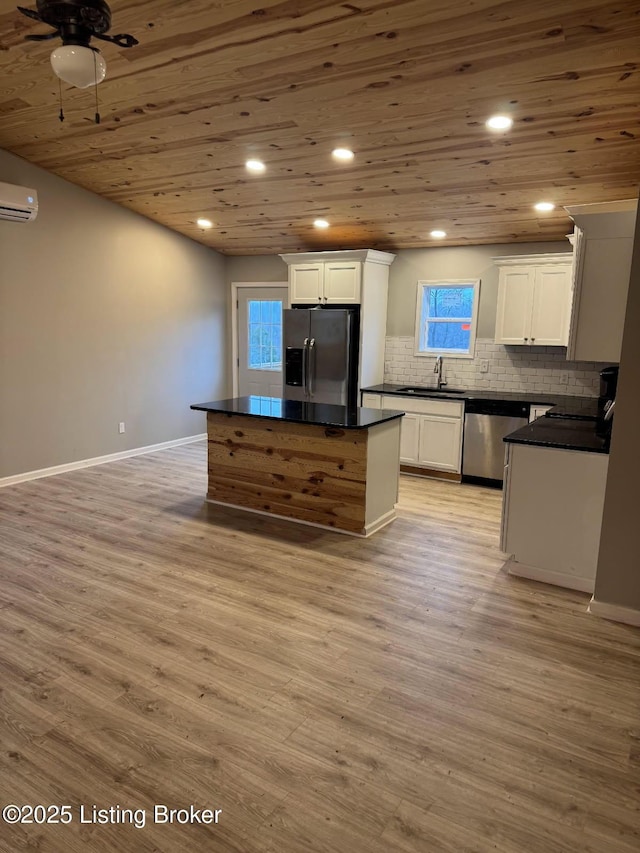 kitchen with sink, a center island, an AC wall unit, appliances with stainless steel finishes, and white cabinets