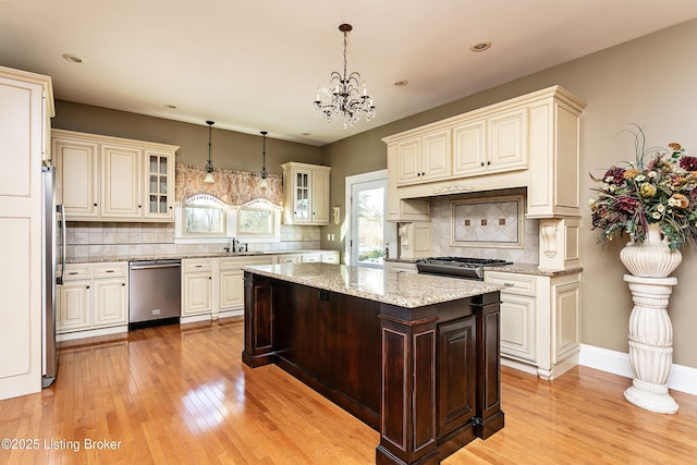 kitchen featuring decorative light fixtures, tasteful backsplash, light stone countertops, a notable chandelier, and appliances with stainless steel finishes