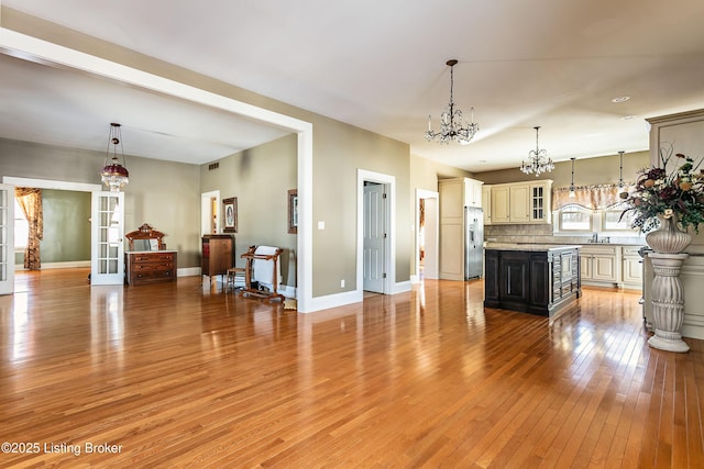 kitchen with a kitchen island, light hardwood / wood-style floors, decorative light fixtures, and stainless steel refrigerator with ice dispenser