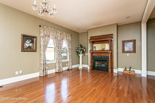 unfurnished living room featuring a premium fireplace, a chandelier, and hardwood / wood-style flooring