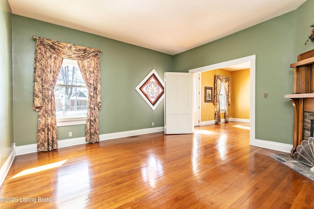 unfurnished living room featuring hardwood / wood-style floors and a stone fireplace