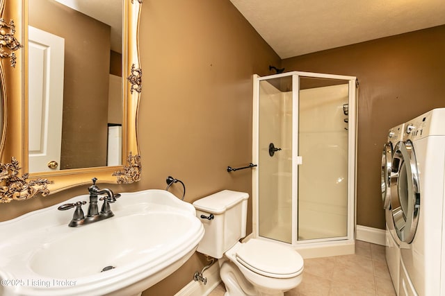 bathroom with sink, tile patterned flooring, toilet, washer and clothes dryer, and an enclosed shower