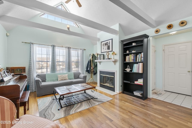 living room featuring light wood-type flooring, ceiling fan, and vaulted ceiling with beams