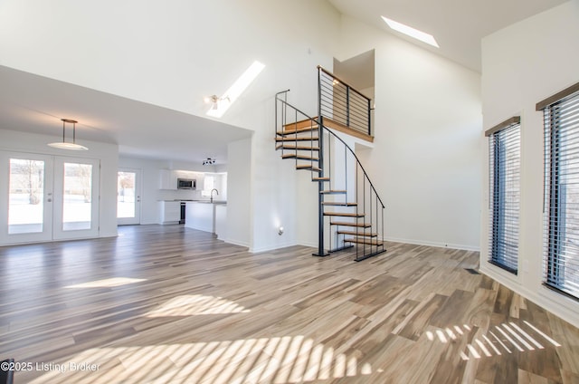 unfurnished living room featuring a skylight, french doors, hardwood / wood-style floors, and sink