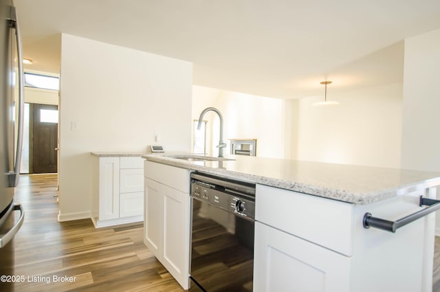 kitchen featuring sink, white cabinetry, black dishwasher, light hardwood / wood-style floors, and pendant lighting