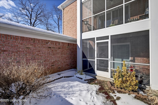 view of snowy exterior with a sunroom