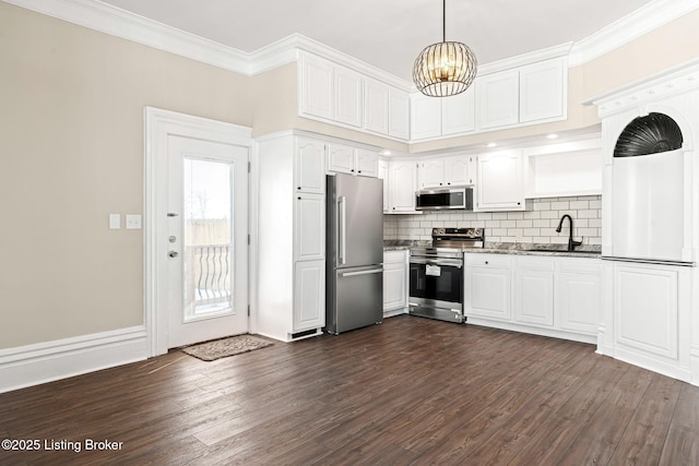 kitchen with pendant lighting, white cabinets, appliances with stainless steel finishes, sink, and backsplash