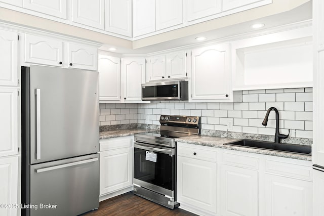 kitchen with tasteful backsplash, dark hardwood / wood-style floors, sink, white cabinetry, and appliances with stainless steel finishes