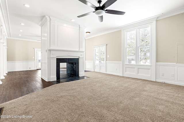 unfurnished living room featuring ceiling fan, ornamental molding, a multi sided fireplace, and dark carpet