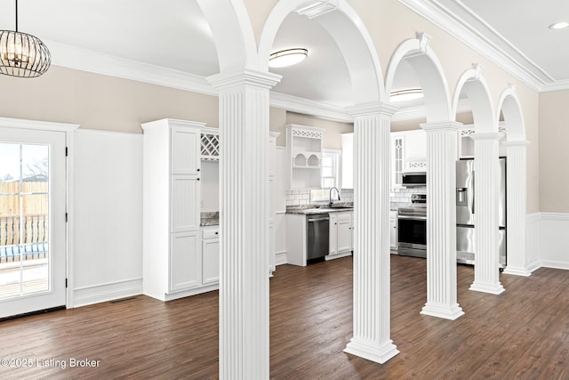 interior space featuring white cabinets, stainless steel appliances, and ornate columns