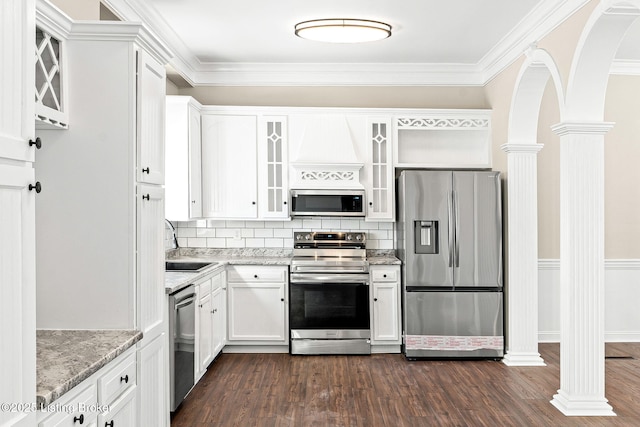 kitchen featuring light stone countertops, stainless steel appliances, white cabinets, and decorative columns