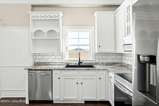 kitchen featuring white cabinetry, appliances with stainless steel finishes, decorative backsplash, stone countertops, and sink