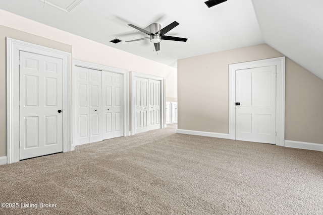 unfurnished bedroom with ceiling fan, lofted ceiling, carpet floors, and multiple closets