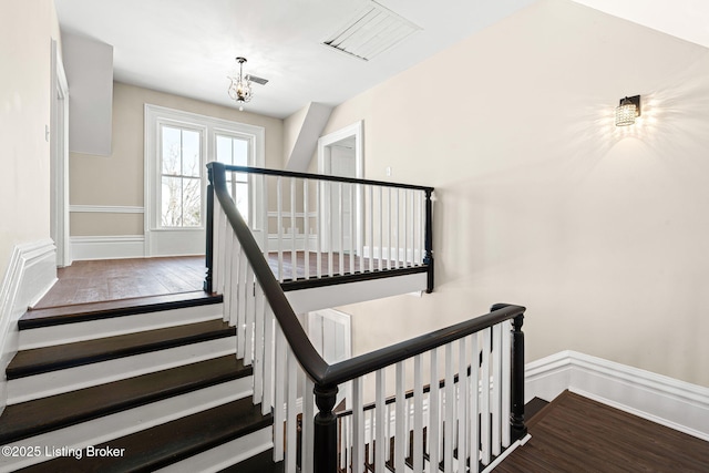 staircase featuring wood-type flooring and a notable chandelier