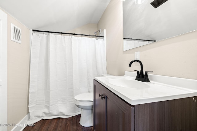 bathroom featuring toilet, vaulted ceiling, wood-type flooring, and vanity