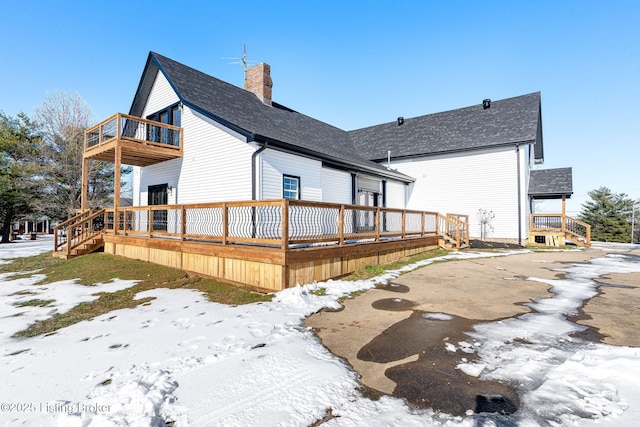 snow covered rear of property with a balcony