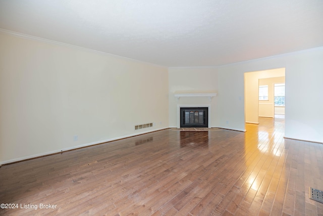 unfurnished living room with hardwood / wood-style floors and crown molding