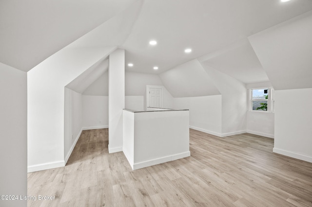 additional living space featuring lofted ceiling and light hardwood / wood-style flooring