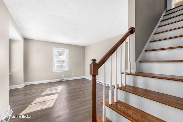 staircase featuring wood-type flooring and a textured ceiling