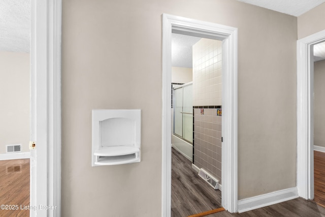 corridor featuring dark wood-type flooring and a textured ceiling