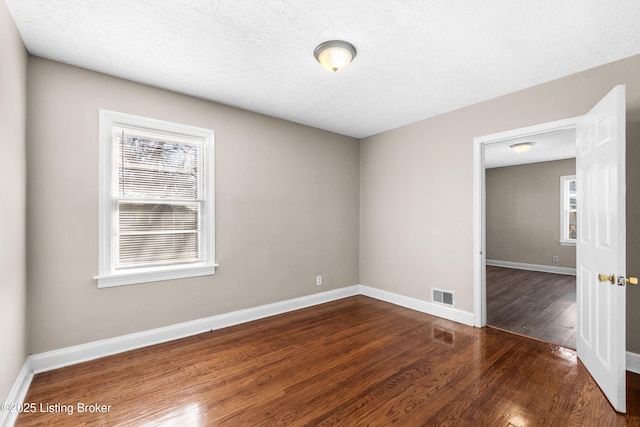 empty room featuring dark wood-type flooring and a textured ceiling