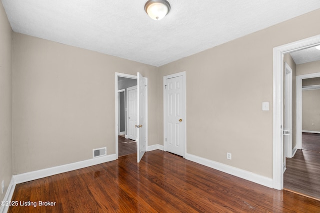 unfurnished bedroom featuring dark wood-type flooring and a closet