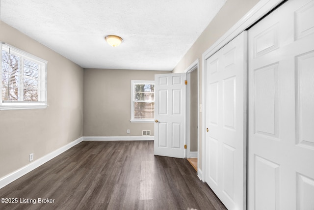 unfurnished bedroom with dark hardwood / wood-style flooring, a closet, and a textured ceiling