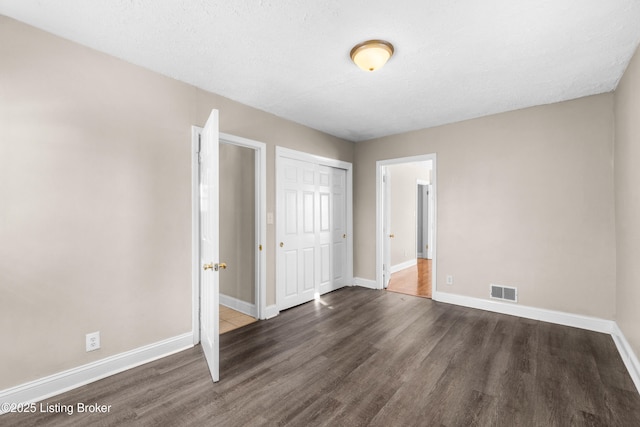 unfurnished bedroom featuring dark hardwood / wood-style flooring, a closet, and a textured ceiling