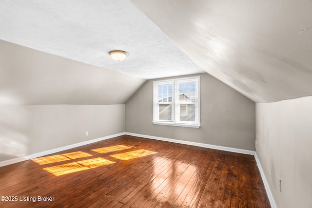 bonus room with dark hardwood / wood-style flooring, vaulted ceiling, and a textured ceiling