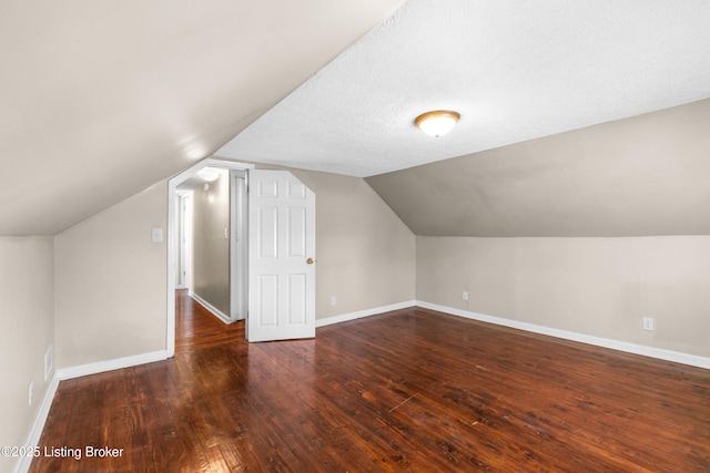 bonus room with dark hardwood / wood-style flooring, vaulted ceiling, and a textured ceiling