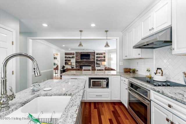 kitchen featuring white cabinetry, a brick fireplace, appliances with stainless steel finishes, dark hardwood / wood-style flooring, and sink