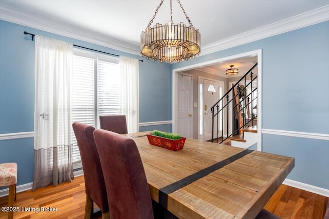 dining space featuring hardwood / wood-style floors, ornamental molding, and a notable chandelier