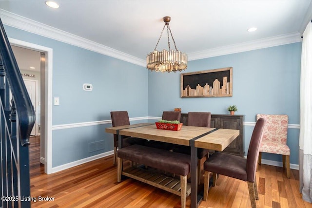 dining area featuring hardwood / wood-style floors, ornamental molding, and a notable chandelier