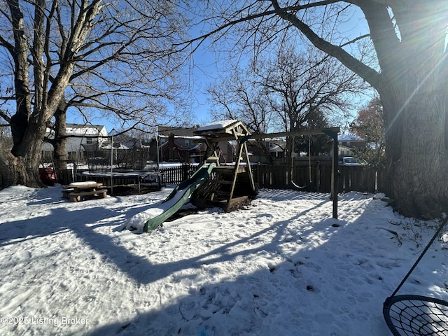 snowy yard with a trampoline and a playground