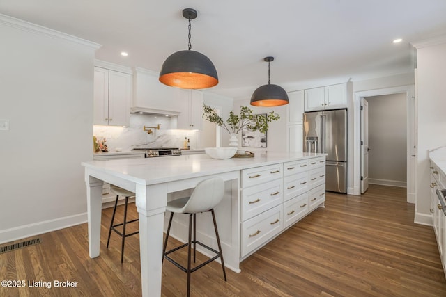 kitchen with custom exhaust hood, white cabinets, high quality fridge, and a kitchen island