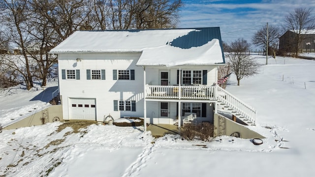 snow covered back of property featuring a garage and a porch