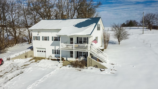 snow covered rear of property featuring a garage