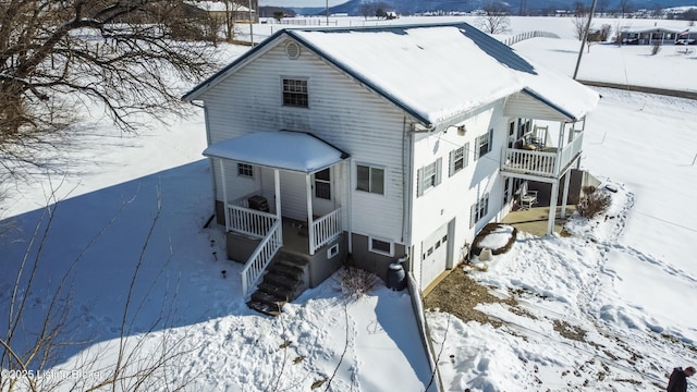 snow covered rear of property with covered porch