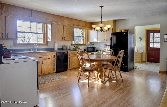 kitchen with light hardwood / wood-style floors, black appliances, pendant lighting, sink, and a chandelier