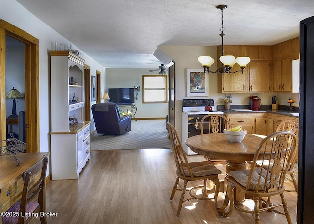 dining room with a textured ceiling, ceiling fan with notable chandelier, and light hardwood / wood-style flooring