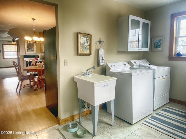 laundry room featuring light tile patterned floors, a chandelier, washing machine and clothes dryer, and sink