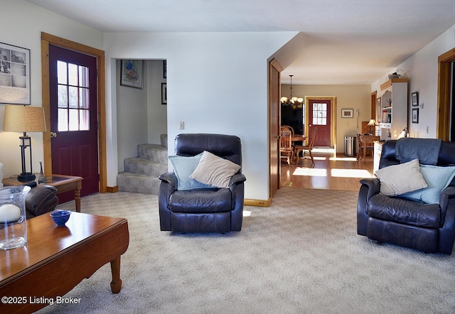 living room featuring light carpet, a healthy amount of sunlight, and a notable chandelier