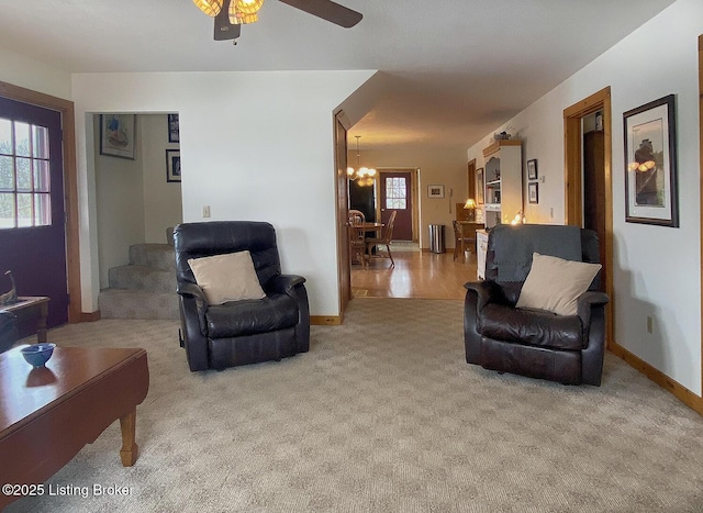 living room with ceiling fan with notable chandelier and light carpet