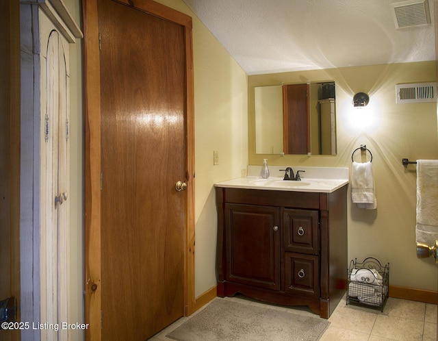 bathroom with lofted ceiling, vanity, tile patterned flooring, and a textured ceiling