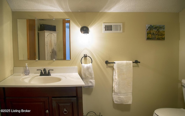 bathroom featuring a textured ceiling, toilet, and vanity