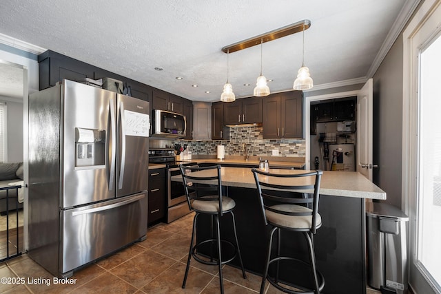 kitchen with appliances with stainless steel finishes, decorative light fixtures, a kitchen breakfast bar, dark brown cabinets, and a center island