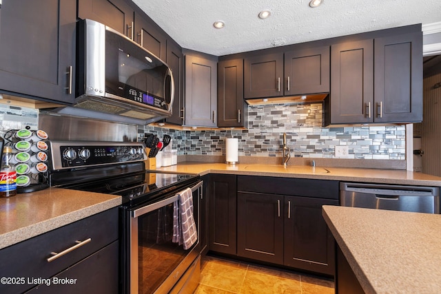 kitchen featuring backsplash, light tile patterned flooring, sink, appliances with stainless steel finishes, and dark brown cabinets