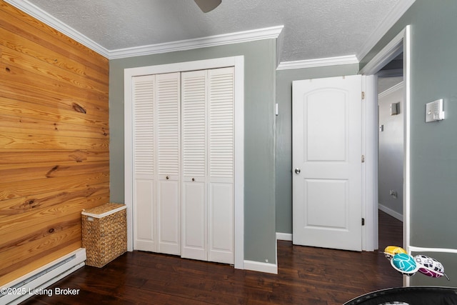 unfurnished bedroom with wood walls, a baseboard radiator, a closet, a textured ceiling, and ornamental molding