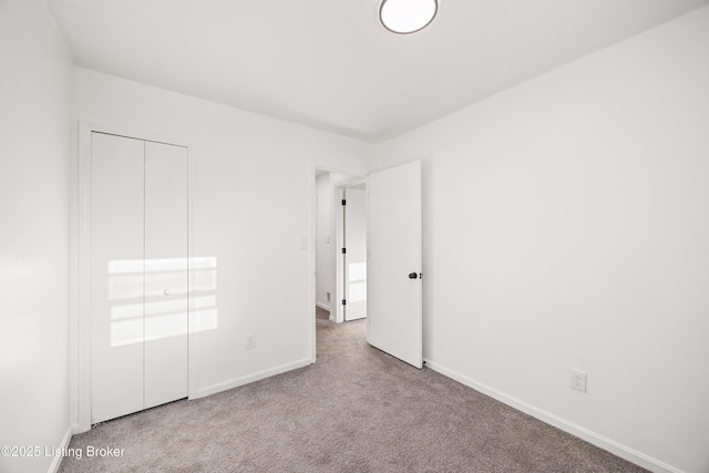 unfurnished bedroom featuring light colored carpet and a closet